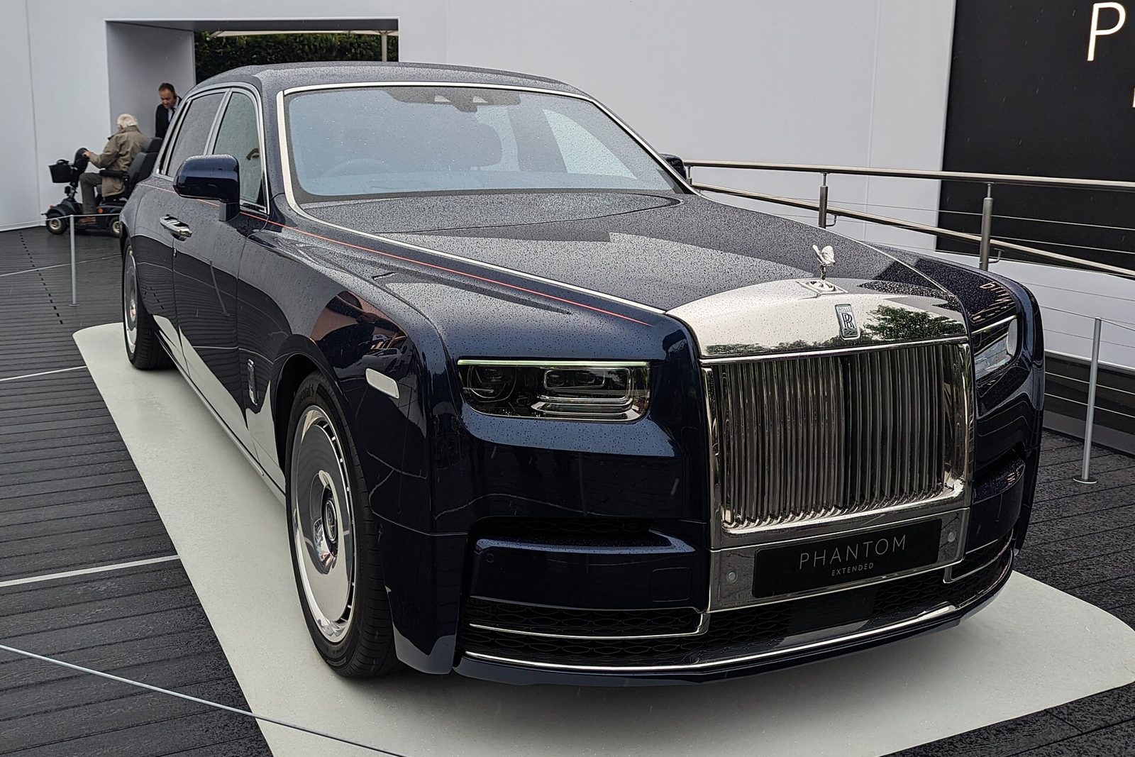Executive saloon with driver waiting outside a modern office building